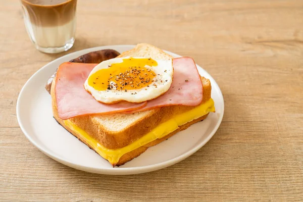 homemade bread toasted cheese topped ham and fried egg with pork sausage and coffee for breakfast