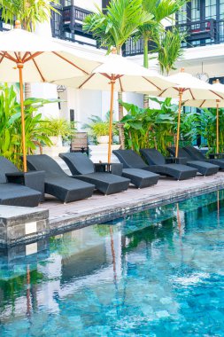 Yüzme havuzu etrafında şemsiye ve havuz sandalyesi - tatil ve seyahat tatili kavramı