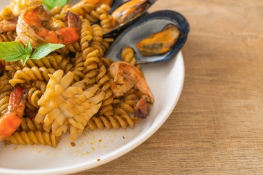 Deniz ürünleri ve fesleğen soslu kızarmış spiral makarna. Füzyon yemek tarzı.