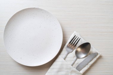 Ahşap zemin üzerinde bıçak, çatal ve kaşık olan boş tabak veya tabak