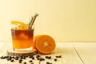 Bir bardak buzlu americano sade kahve ve biberiye ve tarçınla süslenmiş portakal ve limon suyu.