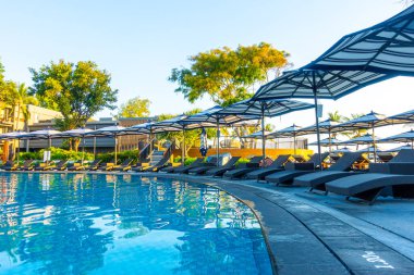 Seyahat tatili konsepti için otel otelinde yüzme havuzunun etrafında şemsiye ve havuz yatağı.