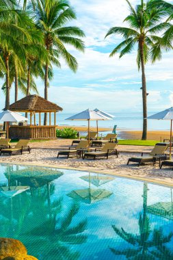 Otelde açık havuzda güzel bir şemsiye ve sandalye ve gün batımında hindistan cevizi palmiyesi ağacı olan bir tatil ve tatil konsepti.