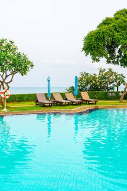 Sandalye havuzu ya da yüzme havuzu etrafında şemsiye olan yatak havuzu