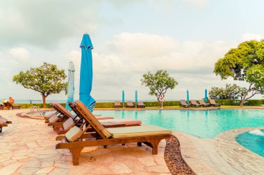 Tayland 'da Pattaya' da deniz plajı geçmişi olan havuz etrafında havuz ve şemsiye.