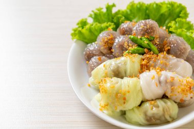 Şeffaf toplara Saku Sai Moo ya da Buharlı Tapioca Köfte Topları ve (Kow Griep Pag Mor) Domuz Buharlı Pirinç Paketleri ya da Haşlanmış Pirinç Kabuklu Mantı denir.