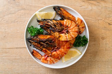 grilled tiger prawns or shrimps with lemon on plate clipart