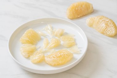 Taze soyulmuş zeytin, greyfurt ya da beyaz tabakta Shaddock.