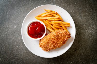 Kızarmış tavuk göğsü fileto biftek yanında patates kızartması ve ketçap.