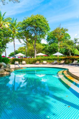 Güzel tropikal plaj ve deniz şemsiyesi ve sandalyesi otel tatil ve tatil için yüzme havuzunda.