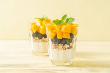 Ev yapımı taze mango ve yoğurt ve granola ile taze yaban mersini. Sağlıklı yemek tarzı.