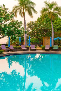 Gün batımında yüzme havuzunda şemsiyeli plaj sandalyesi ya da bilardo yatağı