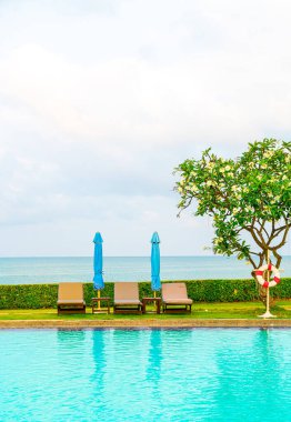 Sandalye havuzu ve şemsiyeyle okyanus arka planında yüzme havuzu