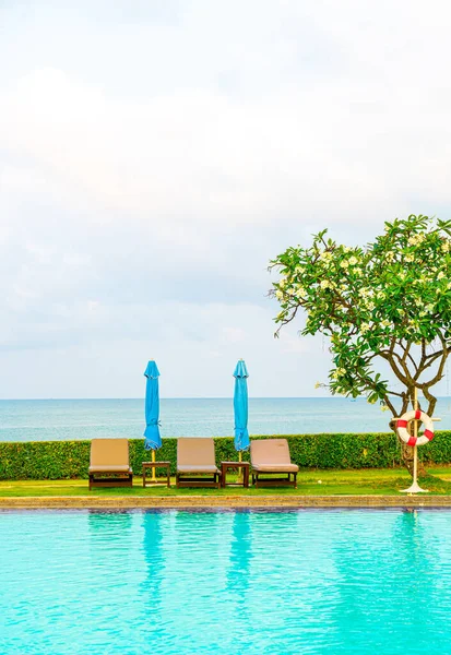 Sandalye havuzu ve şemsiyeyle okyanus arka planında yüzme havuzu