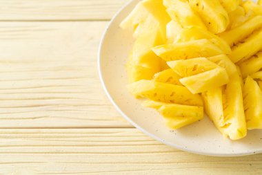Beyaz tabakta dilimlenmiş taze ananas.