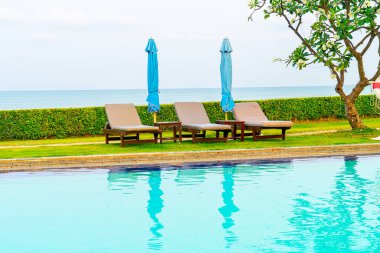 Sandalye havuzu ya da yüzme havuzu etrafında şemsiye olan yatak havuzu