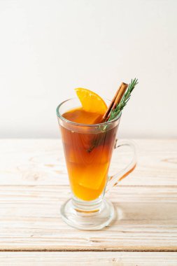 Bir bardak buzlu americano sade kahve ve ahşap arka planda biberiye ve tarçınla süslenmiş portakal ve limon suyu.