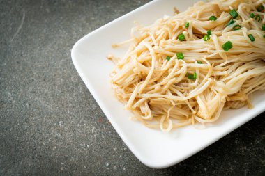 Karıştırılmış altın iğneli mantar, beyaz tabakta tereyağı.