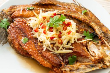 Balık soslu kızarmış deniz levreği balığı ve tabakta baharatlı salata.