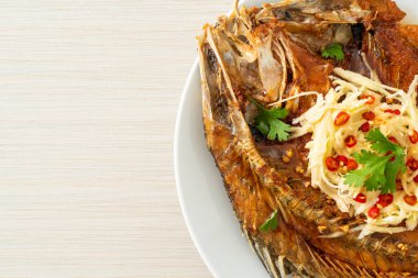 Balık soslu kızarmış deniz levreği balığı ve tabakta baharatlı salata.