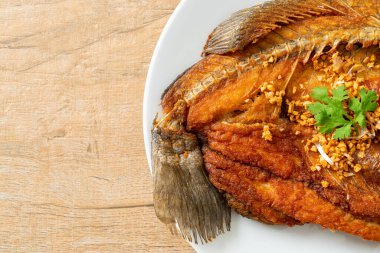 Tabakta sarımsaklı kızarmış deniz levreği balığı.