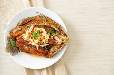 Balık soslu kızarmış deniz levreği balığı ve tabakta baharatlı salata.