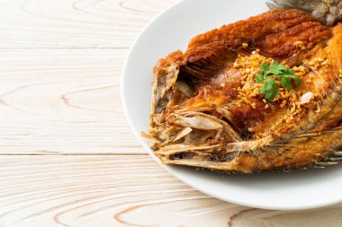 Tabakta sarımsaklı kızarmış deniz levreği balığı.
