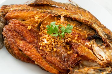 Tabakta sarımsaklı kızarmış deniz levreği balığı.