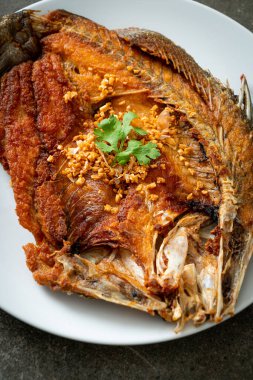 Tabakta sarımsaklı kızarmış deniz levreği balığı.