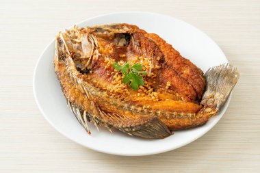 Tabakta sarımsaklı kızarmış deniz levreği balığı.