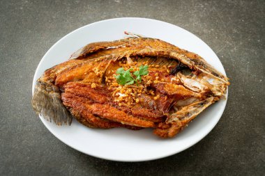 Tabakta sarımsaklı kızarmış deniz levreği balığı.