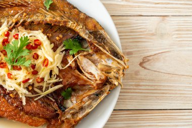 Balık soslu kızarmış deniz levreği balığı ve tabakta baharatlı salata.