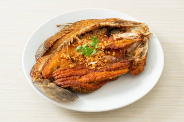 Tabakta sarımsaklı kızarmış deniz levreği balığı.