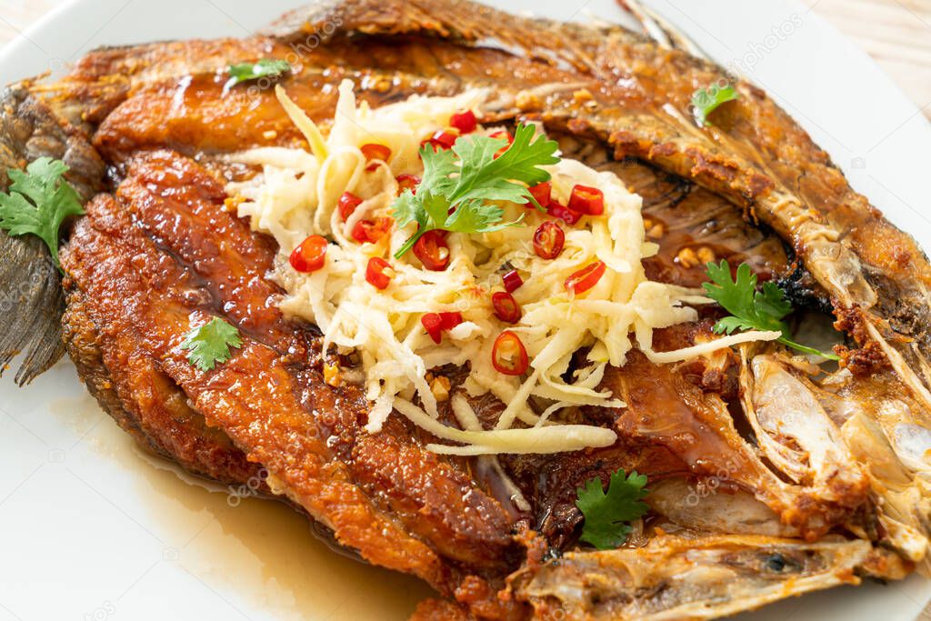Fried Sea Bass Fish with Fish Sauce and Spicy Salad on plate
