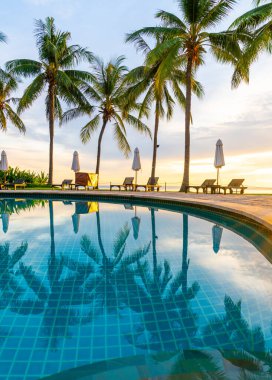 Şemsiye ve sandalye oteldeki yüzme havuzunda sabah gün doğumuyla birlikte - tatil ve tatil konsepti