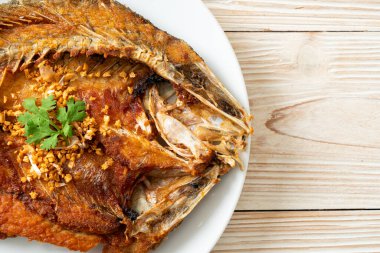 Tabakta sarımsaklı kızarmış deniz levreği balığı.