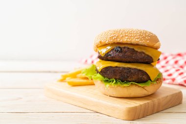 Peynirli ve patates kızartmalı hamburger veya sığır burger. Sağlıksız yemek tarzı.