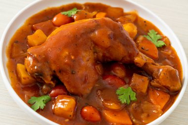 Domatesli ev yapımı tavuk güveci, soğan, havuç ve patates tabakta.