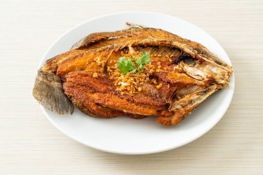 Tabakta sarımsaklı kızarmış deniz levreği balığı.