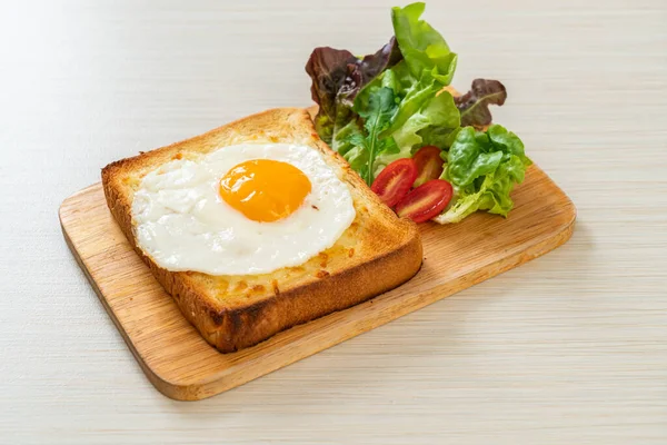 homemade bread toasted with cheese and fried egg on top with vegetable salad for breakfast