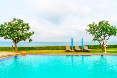 Sandalye havuzu ve şemsiyeyle okyanus arka planında yüzme havuzu