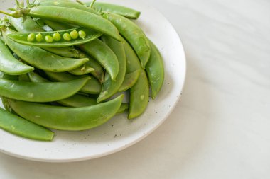 Taze yeşil bezelyeler beyaz tabakta