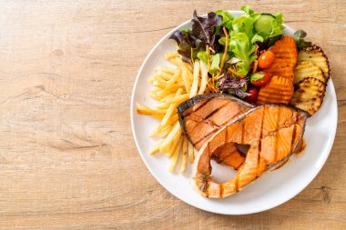 Çift ızgara somon bifteği, sebze ve patates kızartması.
