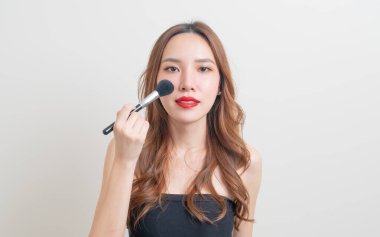 Beyaz arka planda makyaj fırçası olan güzel bir Asyalı kadın portresi