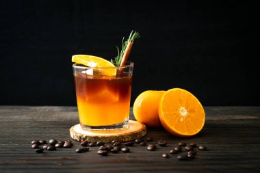 Bir bardak buzlu americano sade kahve ve biberiye ve tarçınla süslenmiş portakal ve limon suyu.