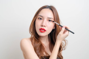 Beyaz arka planda makyaj fırçası olan güzel Asyalı kadın portresi.