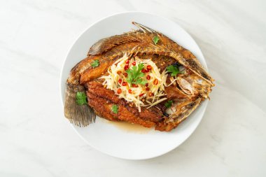 Balık soslu kızarmış deniz levreği balığı ve tabakta baharatlı salata.