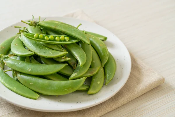 白いプレートに新鮮な甘い緑のエンドウ豆 — ストック写真