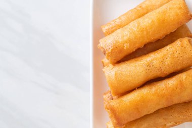 Kızarmış yumurta rulosu ve beyaz tabakta sos.