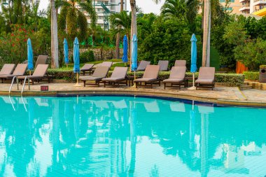 Gün batımında yüzme havuzunda şemsiyeli plaj sandalyesi ya da bilardo yatağı